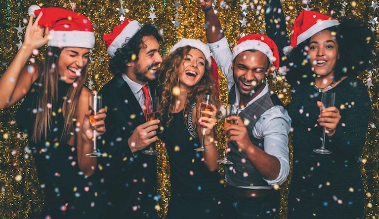 Group of men and women laughing in Christmas hats
