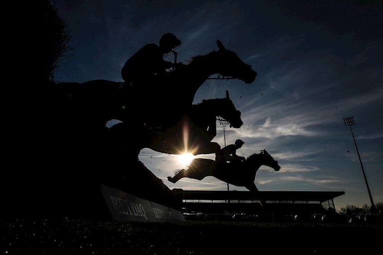 Horses silhouettes jumping a fence at Kempton Park